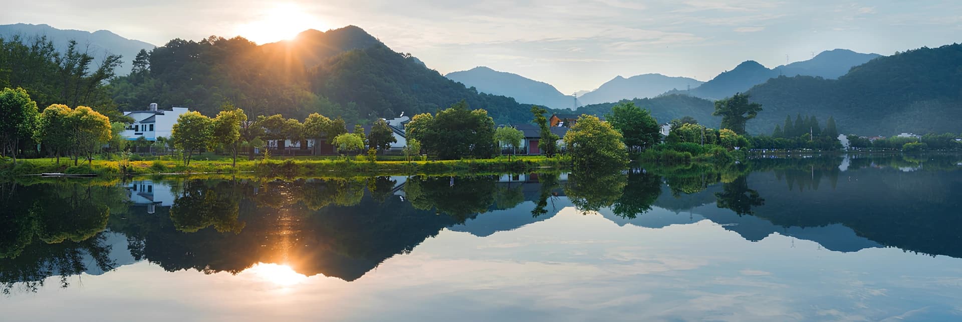expansive aerial shot of a majestic winding river through emerald green wetlands and forests under a soft hazy sunlight